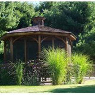 A wooden gazebo surrounded by lush green foliage in a garden setting.