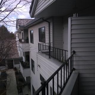 View of an apartment building with balconies and railings under an overcast sky.