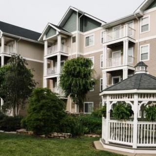 A residential apartment complex with a white gazebo set amidst lush greenery.
