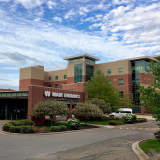 A view of the hospital building at a university campus under a partly cloudy sky.