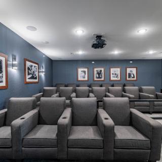 A cozy home theater setup featuring comfortable gray chairs and framed photographs on the wall.
