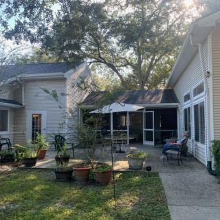 A serene backyard patio with potted plants and outdoor seating under the shade of trees.