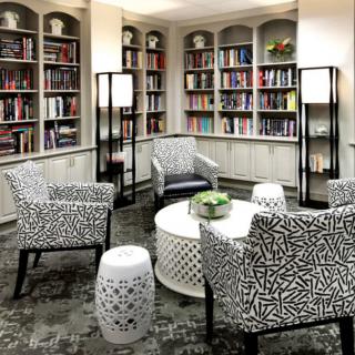 A modern library reading room with patterned armchairs and filled bookshelves.