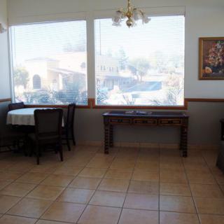 An empty restaurant interior with tables and chairs near large windows.