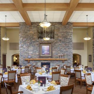 A beautifully set dining room with elegantly arranged tables and a stone fireplace.