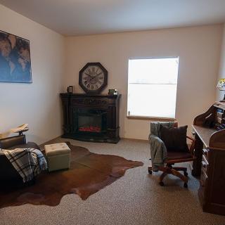 Cozy living room with a fireplace, desk, and armchair.
