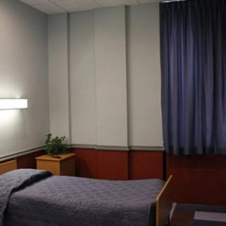 A tidy and minimalist hospital room with a single bed and blue curtains.