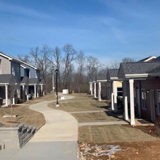 A suburban residential area featuring houses and a central pathway with a clear blue sky.