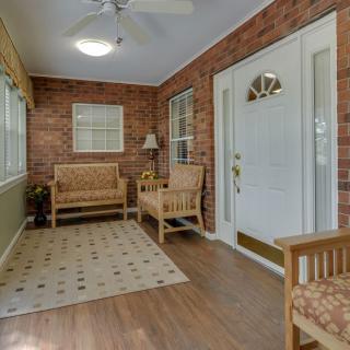 A cozy sunroom featuring wooden furniture, a brick wall, and large windows that allow natural light to fill the space.