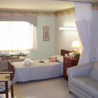A well-lit hospital room with a single bed and cozy furnishings.