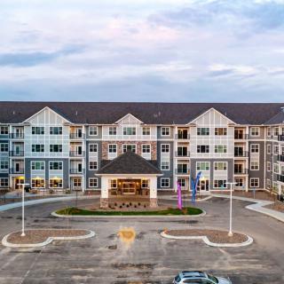 A large residential apartment building with a central entrance and surrounding parking area.
