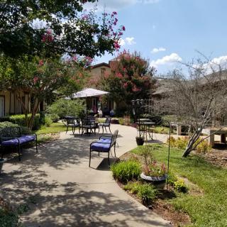 A serene garden with outdoor seating and lush greenery along a winding pathway.