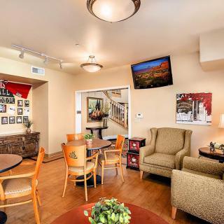 A cozy living room with comfortable seating, a television mounted on the wall, and warm lighting.