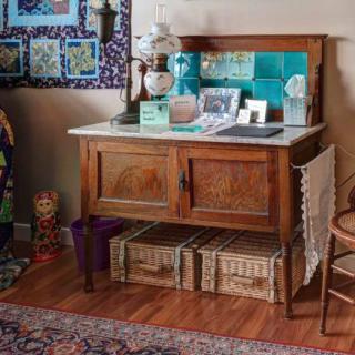A cozy room featuring a vintage wooden sideboard adorned with decorative items and illuminated by a classic table lamp.