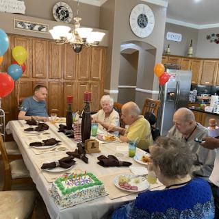 A joyful birthday celebration with friends and family gathered around the dining table.