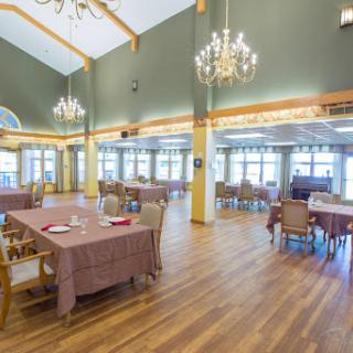 A spacious and elegantly designed dining room featuring chandeliers and wooden floors.