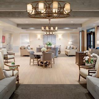 A spacious and elegantly decorated living room with plush seating, ornate chandeliers, and sophisticated decor.