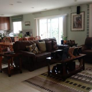 A cozy and well-lit living room with a sofa, coffee table, dining area, and kitchen in the background.