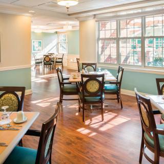 A well-lit dining area with neatly arranged tables and chairs, featuring large windows that allow ample natural light to fill the space.