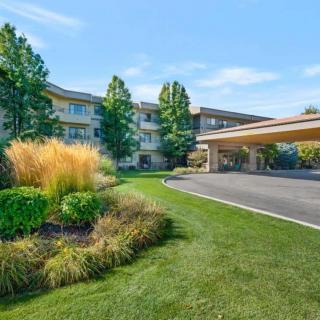A well-manicured hotel entrance with lush greenery and a cover for vehicles.