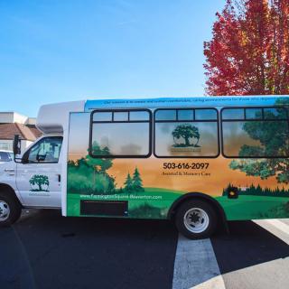 A colorful bus with nature-themed graphics parked in a lot during autumn.