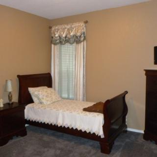 A cozy bedroom with a single bed, nightstand, and elegant curtains.