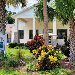 A beautiful house surrounded by palm trees and lush landscaping on a sunny day.