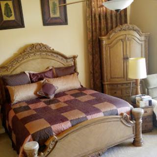 A beautifully decorated bedroom featuring a classic-style bed with ornate detailing and coordinated accessories.
