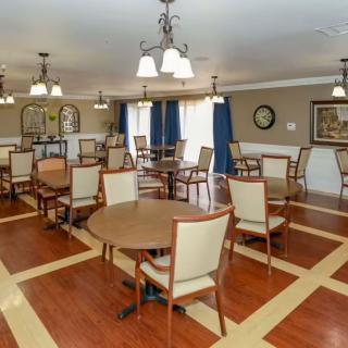 A spacious dining area with neatly arranged tables and chairs, featuring elegant lighting and wood flooring.