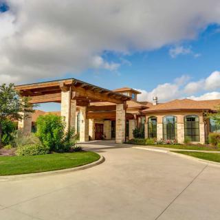 A beautiful luxury home with a large driveway and manicured landscaping under a blue sky.