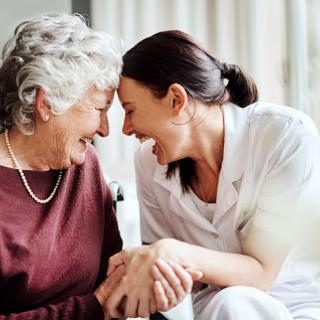 A heartfelt moment shared between an elderly woman and her caregiver, filled with laughter and connection.