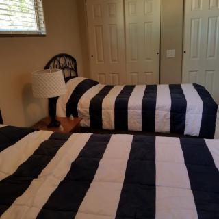 A bedroom with two single beds featuring striped bedding, a lamp, and a window with blinds.
