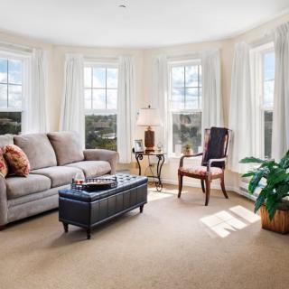 A cozy living room with a sofa, an armchair, and large windows letting in natural light.