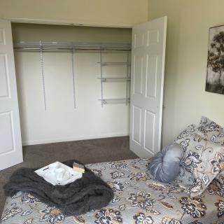 A cozy bedroom with an open closet and a patterned bedspread.