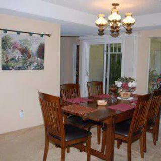 A dining room with a wooden table, chairs, and a chandelier.