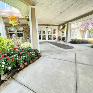 A welcoming building entrance with a covered walkway and a vibrant flower bed.