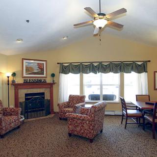 A cozy living room with comfortable seating, a fireplace, and a ceiling fan.