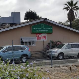 A building displaying a 'Hiring' sign, surrounded by cars and palm trees.