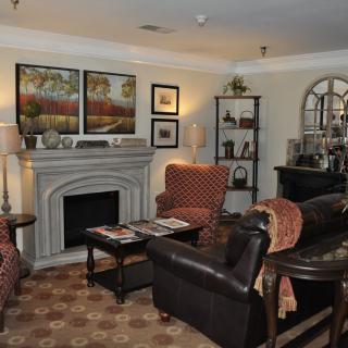 A cozy living room featuring a fireplace, armchairs, and decorative artwork.