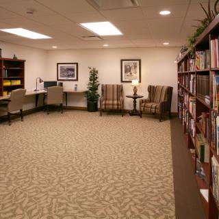 A quiet library space with bookshelves, chairs, and a computer desk.