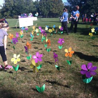 People enjoy a sunny day in the park, surrounded by colorful artificial flowers planted in the grass.