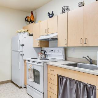 A modern kitchen with light wood cabinets, a white refrigerator, and an electric stove.