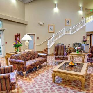 A spacious lobby area featuring classic furniture, decorative elements, and a staircase leading to an upper level.