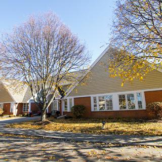 A suburban house surrounded by trees in autumn.