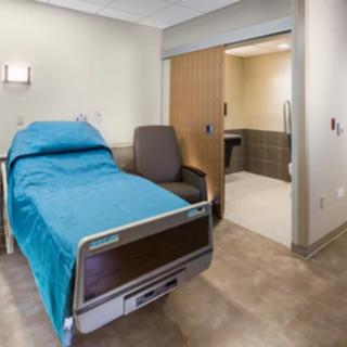 A clean and well-organized hospital room with a bed and a chair.