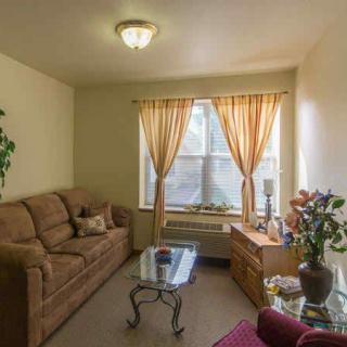 A cozy living room with a sofa, coffee table, and window with curtains.