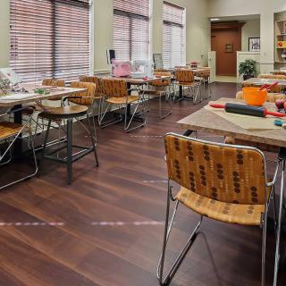 A well-lit classroom with tables and chairs arranged neatly on a wooden floor.
