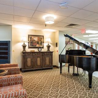 A spacious lobby with a grand piano, elegant furniture, and warm lighting.