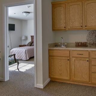 A cozy interior featuring a kitchenette and a bedroom with sunlight streaming in.