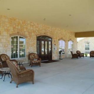 A covered patio area with wicker chairs outside a building entrance.